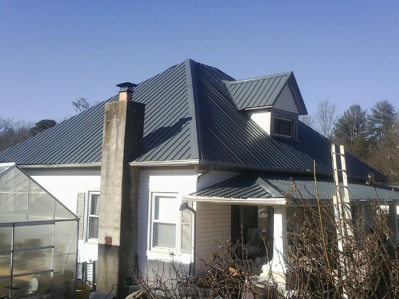 Dark blue standing seam metal roof on a white farmhouse with dormer — Slate & Tile Roof Repair by Roofing Brothers in Dresden