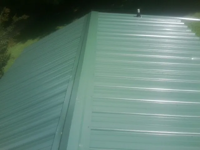New green metal panels meeting at the ridge of a roof — Flat Roof Repair work by our crew in Dresden