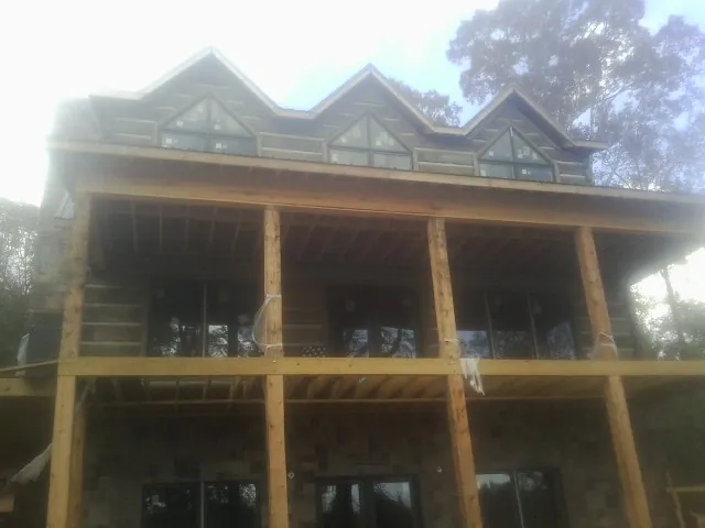 Dormers and porch framing on a large log home under construction — Roof Coating work by our crew in Dresden